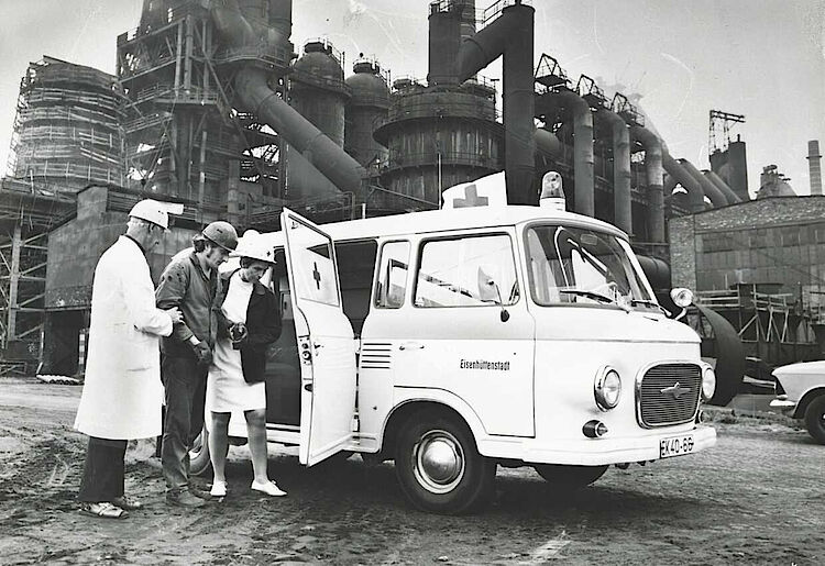 Im Stahlwerk Eisenhüttenstadt bringen Helfer einen verletzten Arbeiter zum Einsatzfahrzeug, um 1970