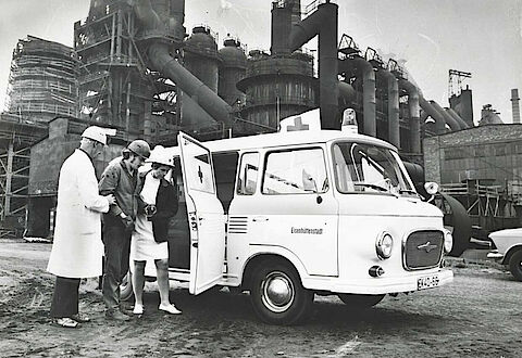 Im Stahlwerk Eisenhüttenstadt bringen Helfer einen verletzten Arbeiter zum Einsatzfahrzeug, um 1970