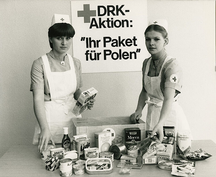 Deutsche Rotkreuzschwestern mit einem Standardpaket im Wert von fünfzig DM, das Lebensmittel und Hygieneartikel enthält (DRK)