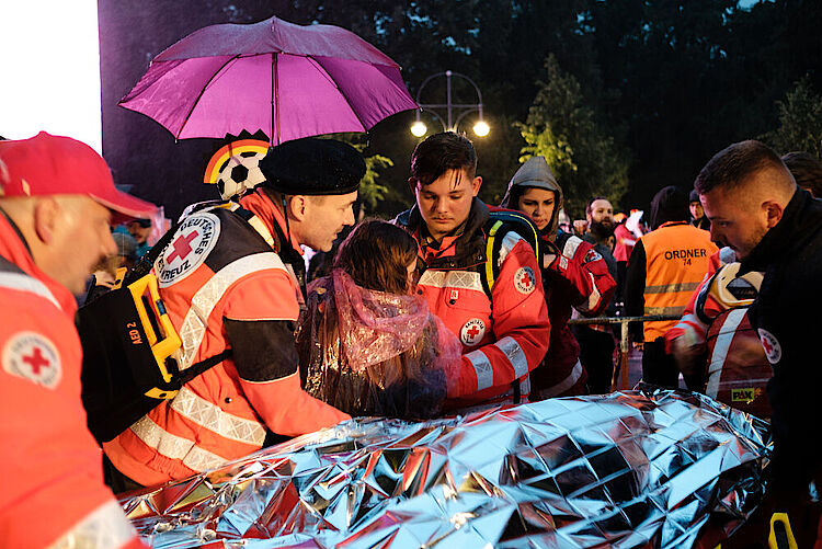 Einsatz von ehrenamtlichen Helfern des DRK-Sanitätsdienstes beim Public Viewing auf der Fanmeile zur Fußball-Weltmeisterschaft 2018: Eine Besucherin wird von Helfern auf eine Trage gelegt, 17. Juni 2018         