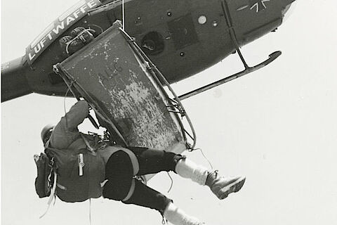 Ein Hubschrauber der Luftwaffe zieht eine Trage (Akja) mit einem Verletzten und dem Bergretter hoch 
