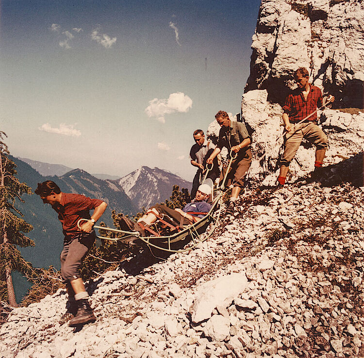 Einsatz der Bergwacht: Helfer beim Transport eines verunglückten Bergsteigers mit einer Gebirgstrage, um 1960